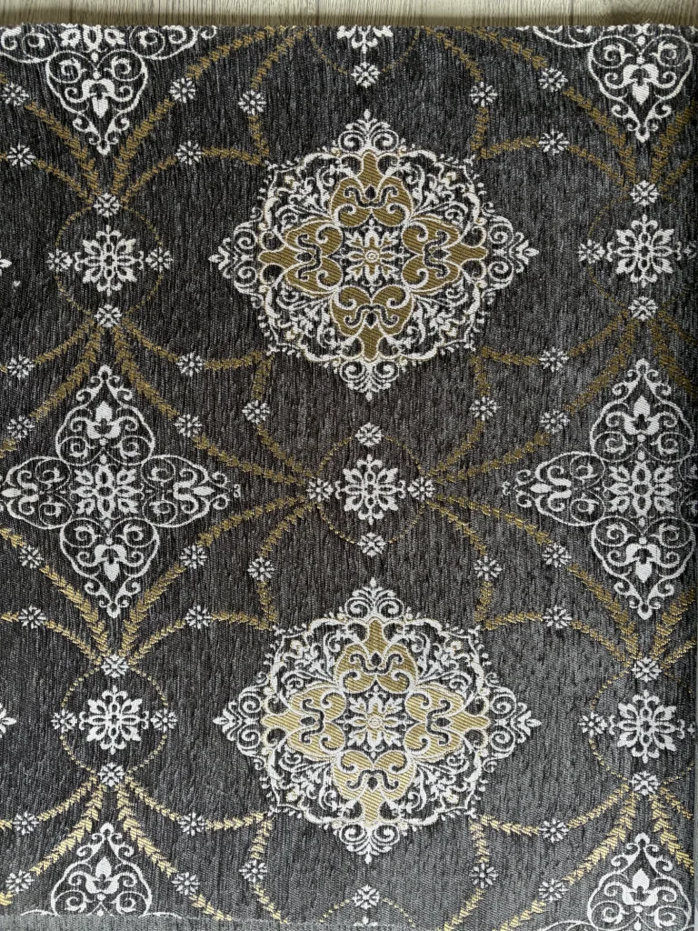 Anthracite chenille jacquard upholstery fabric with repeating white and gold medallions in a close repeat