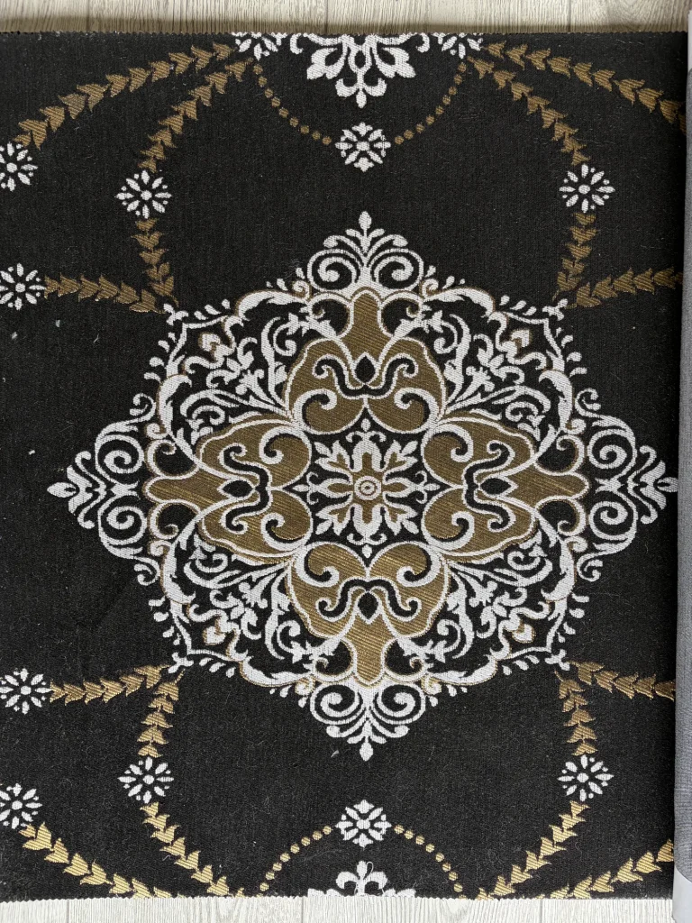 Black chenille upholstery fabric swatch with a large white and gold medallion and gold leaf garlands