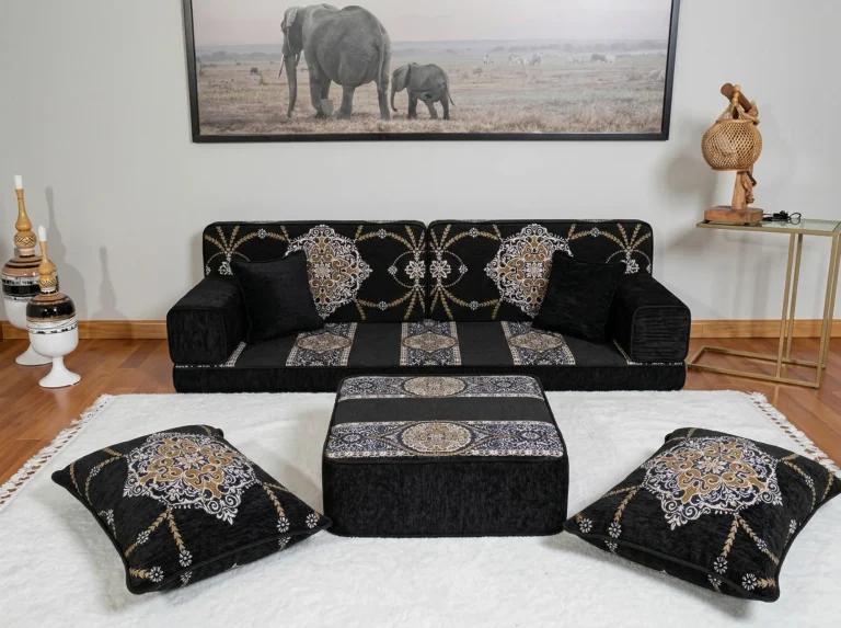 Black chenille Arabic sofa at floor level with gold medallion cushions, ottoman and two floor cushions