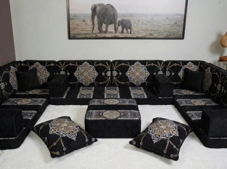 Black and gold medallion floor sofa set in a U shape with a matching ottoman on a white shaggy rug