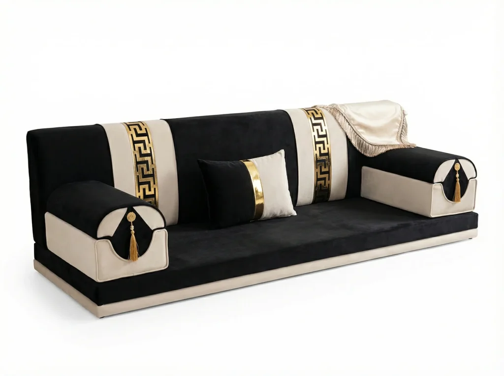 Black and cream velvet majlis sofa set piece with gold key-pattern strips, bolster armrests and a fringed cream throw
