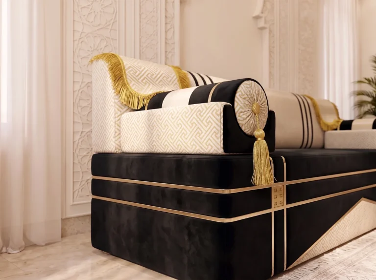 Close-up of a striped bolster armrest with a gold tassel on a black and cream majlis sofa with gold trim lines