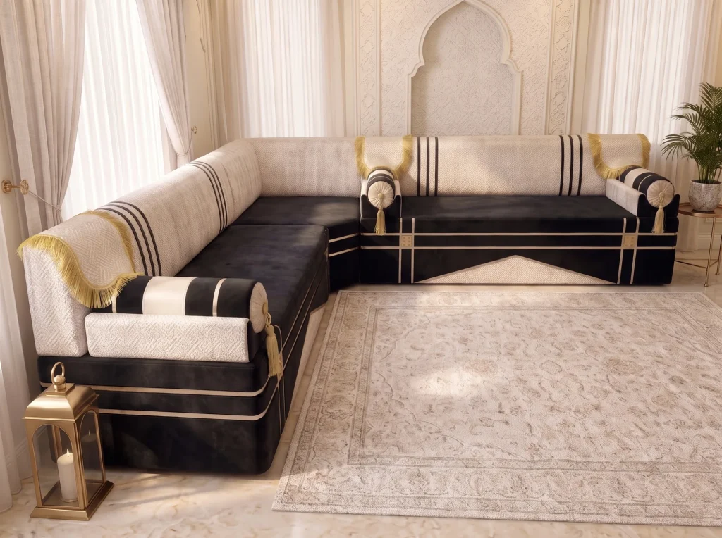 Black and cream L-shaped majlis seen from the armrest end, with gold fringe and striped bolsters