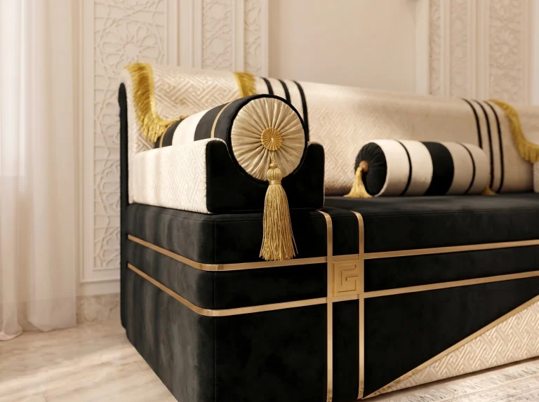 Close-up of a pleated gold rosette armrest and tassel on a black velvet majlis sofa with a gold key emblem