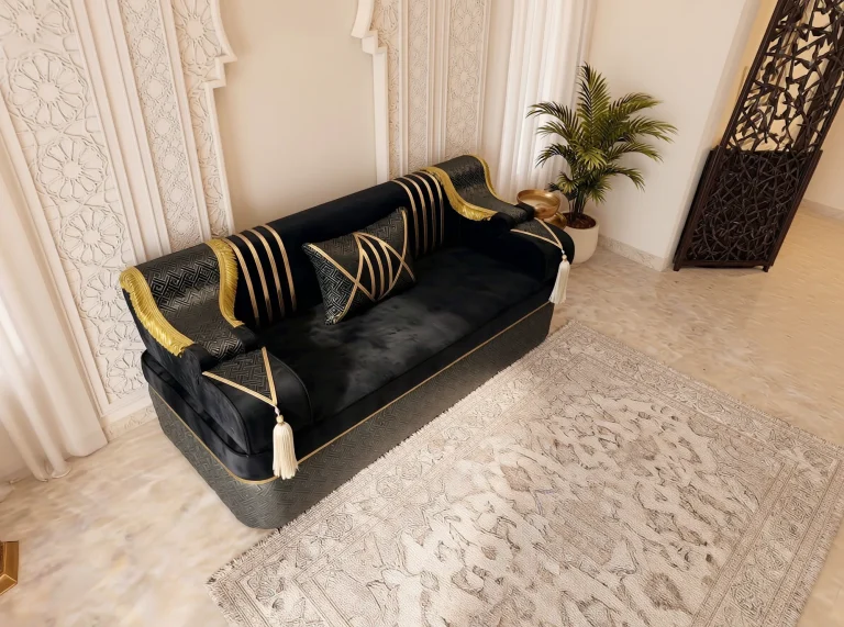 High-angle view of a single black velvet Arabic jalsa seat with gold stripes beside a dark wooden lattice screen