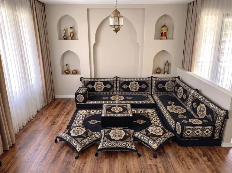 Black and gold medallion floor sofa set in an L shape with ottoman, rug and three tasselled floor cushions