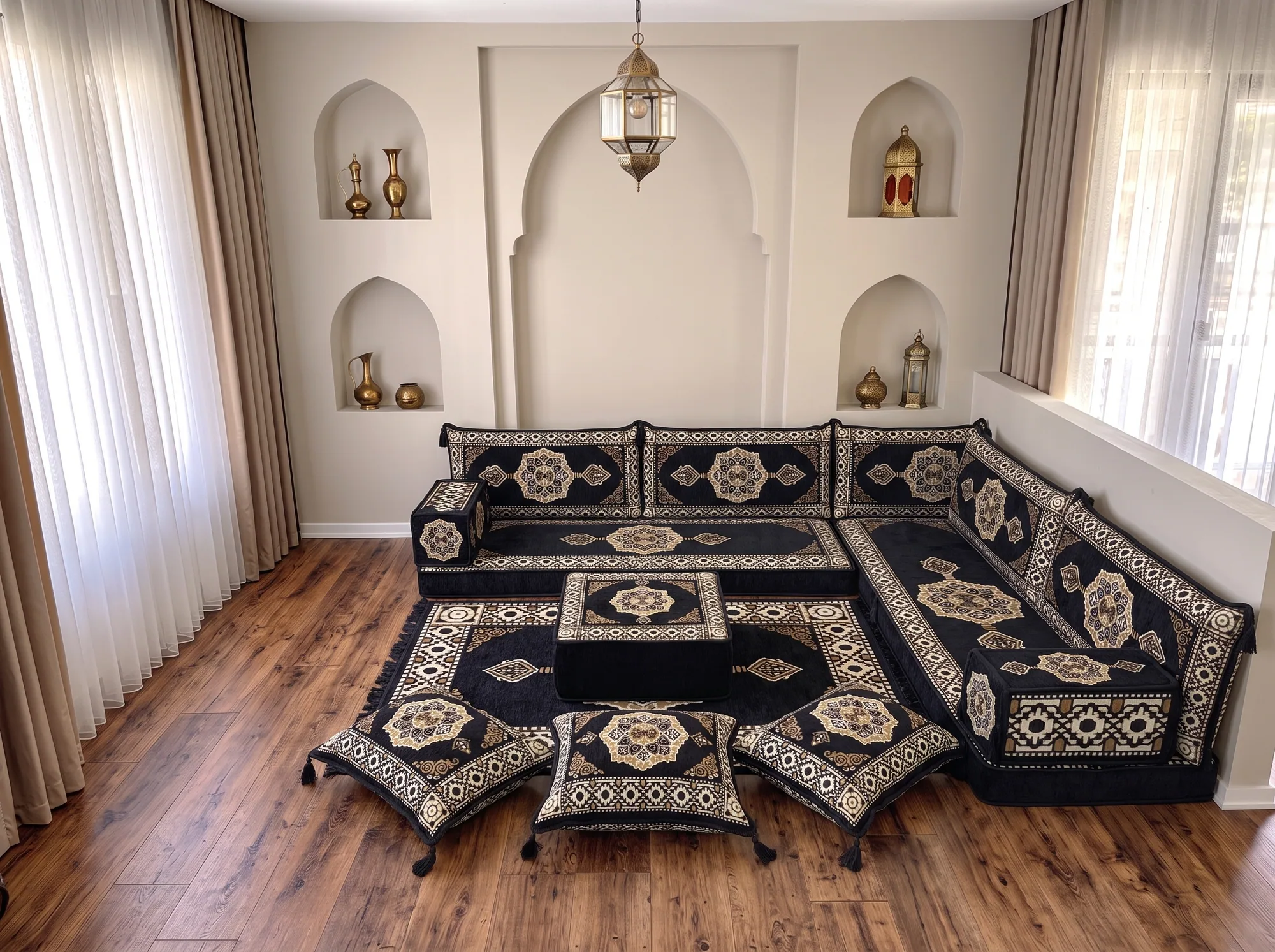 Black and gold medallion floor sofa set in an L shape with ottoman, rug and three tasselled floor cushions