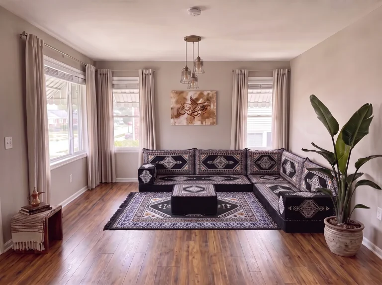 Black kilim floor sofa set in an L shape with a square ottoman on a matching rug in a gray living room