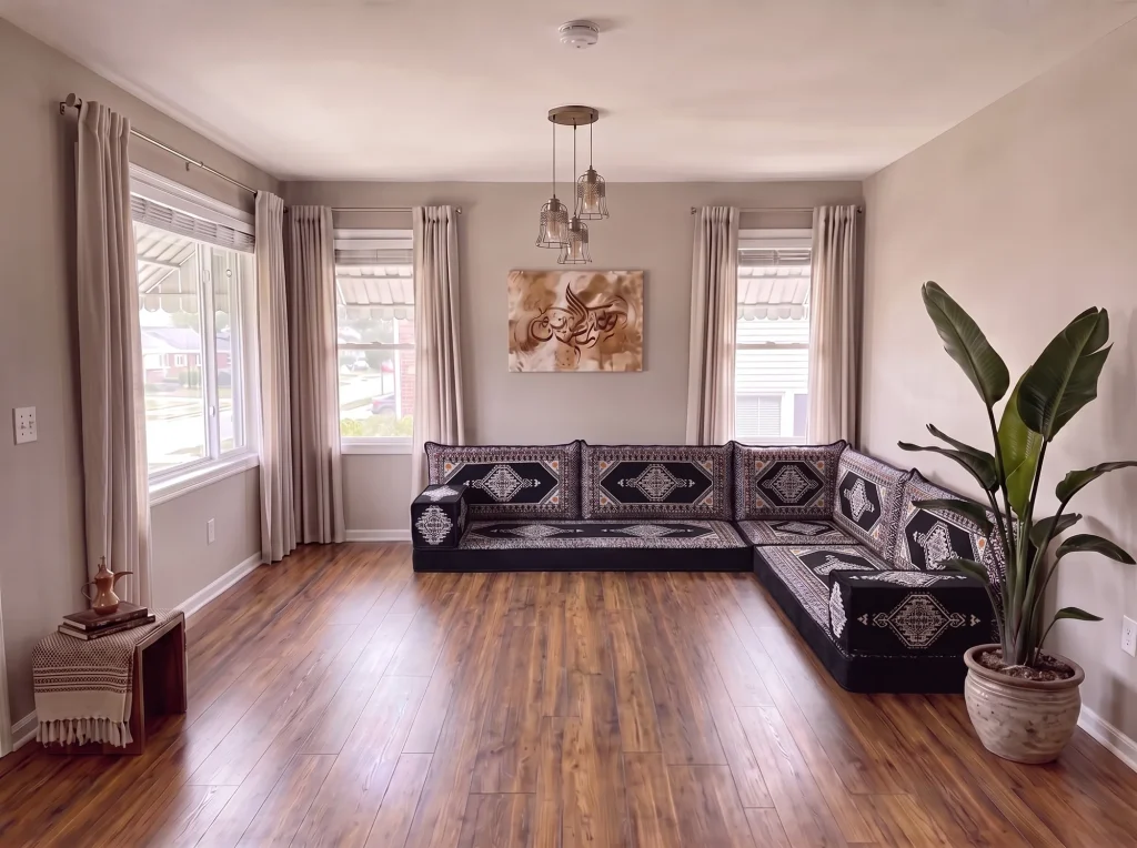 Black and cream kilim floor seating set in an L shape on a bare wooden floor in a gray living room with a plant