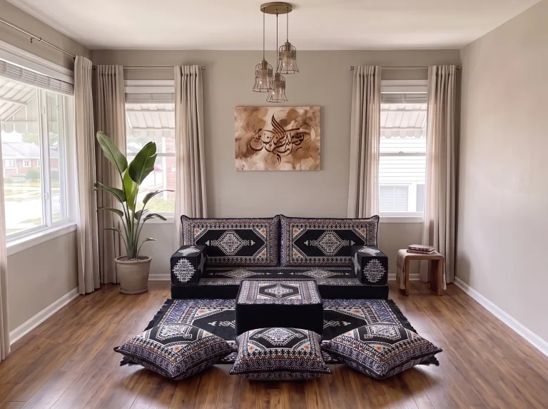 Black kilim Arabic floor sofa seen from the front with ottoman, matching rug and three floor cushions between two windows