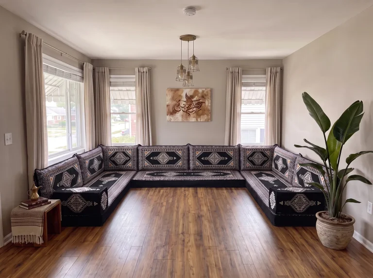 Black and cream kilim Arabic floor sofa in a U shape along three walls, on a bare wooden living room floor