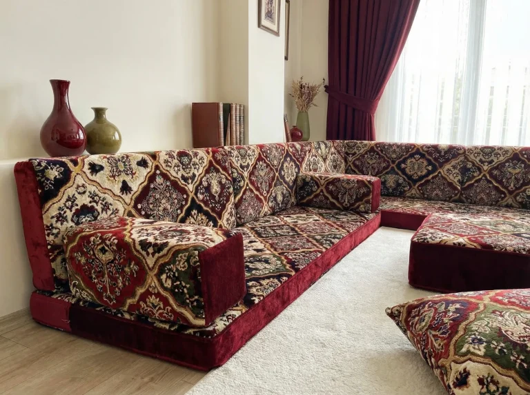 Burgundy velvet diwan floor sofa with a diamond carpet pattern in cream, navy and green, seen from one end