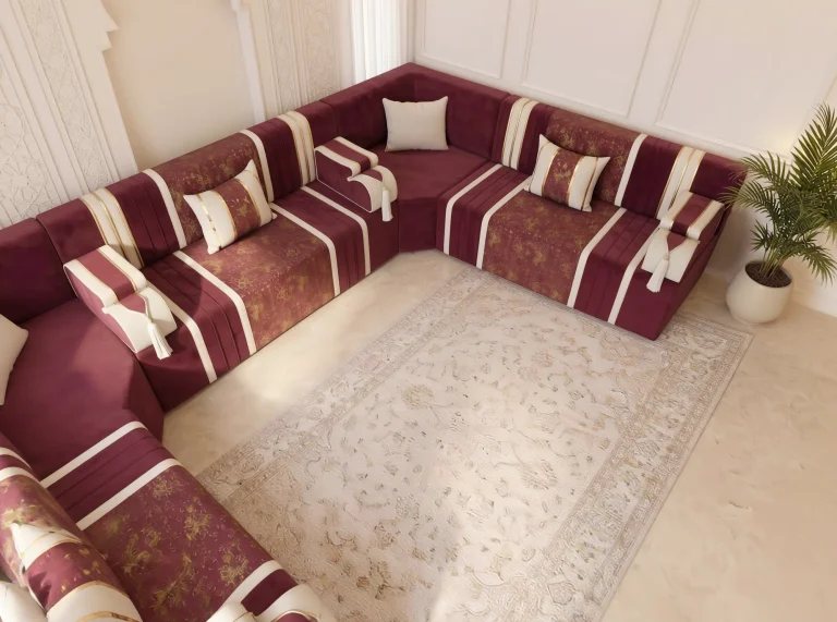 Overhead corner view of a burgundy velvet Arabic majlis with cream stripes, tassel armrests and cream rug