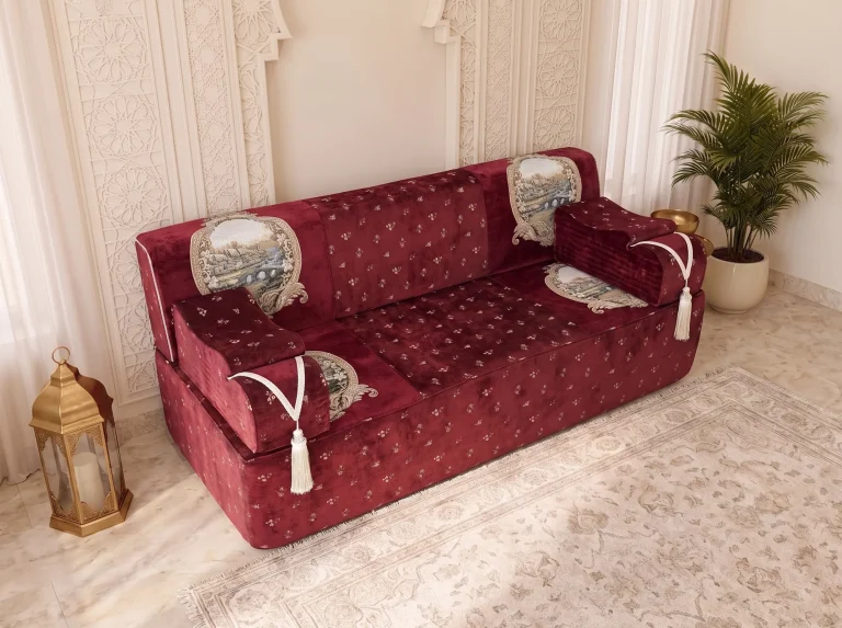 Three-quarter view of a single burgundy velvet majlis sofa with tapestry panels and ribbed armrests