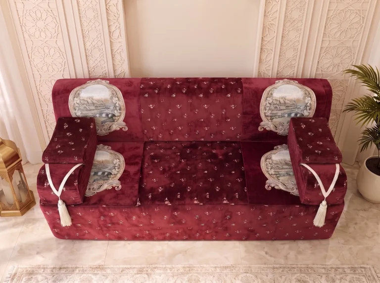Top-down view of a single burgundy velvet majlis seat with four tapestry medallions and tasselled arms