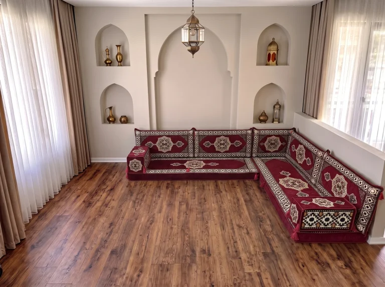 Burgundy Arabic floor sofa with cream medallions and black-and-white borders in an L shape on a bare wooden floor