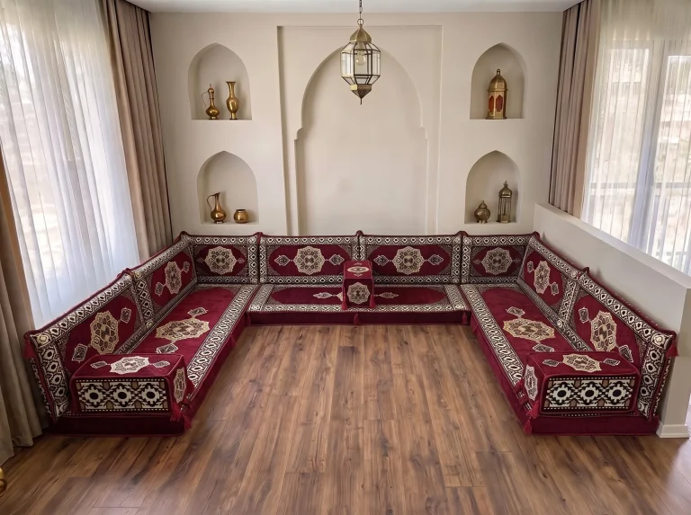 Burgundy medallion U-shaped Arabic floor couch on a bare wood floor in a room with arched niches and brass lanterns