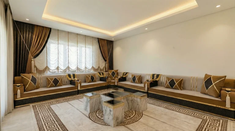 Room after conversion to a caramel and black Arabic majlis along two walls, with marble cube tables and a key-border rug