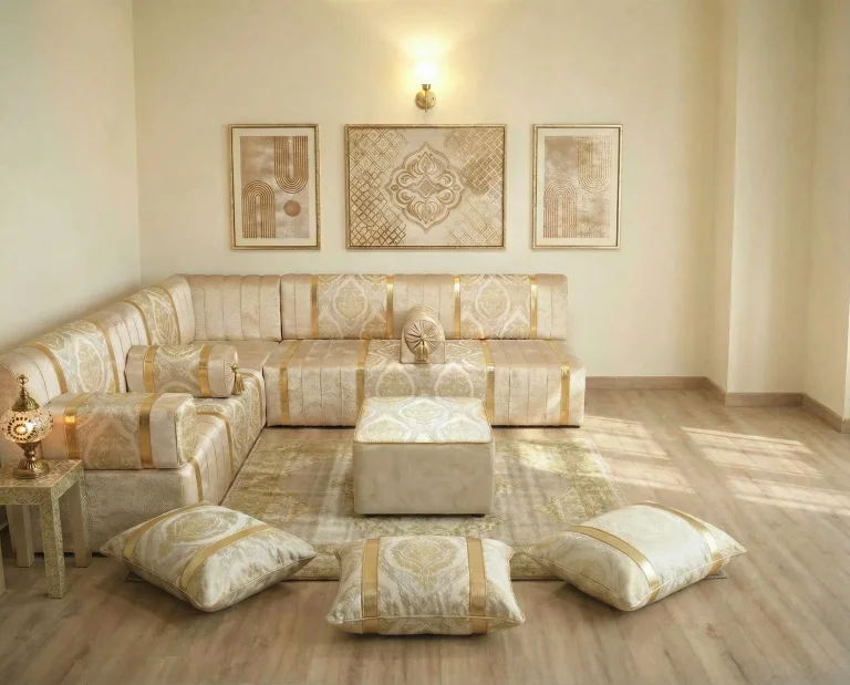 Ivory and gold damask diwan floor sofa in an L shape with pouf and three floor cushions under three framed gold artworks