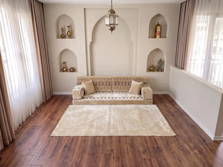 Cream velvet Arabic floor sofa with burgundy cross-stitch bands as a single row with a plain cream rug by arched niches