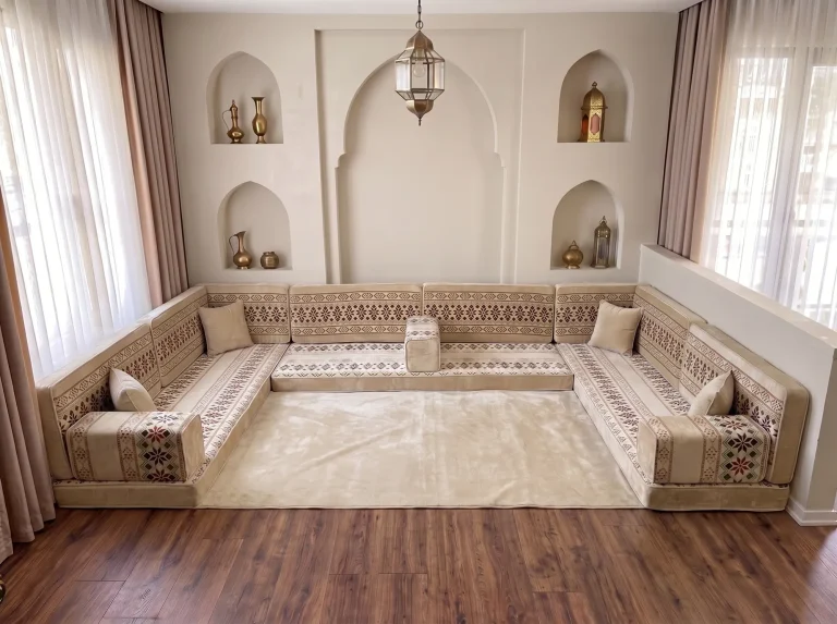 Cream and burgundy Arabic floor sofa in a U shape around a plain cream rug in a room with arched wall niches