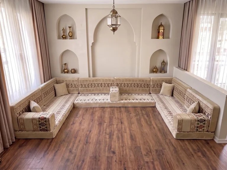 Cream U-shaped floor seating set with burgundy embroidered-look bands on a bare wooden floor below arched niches