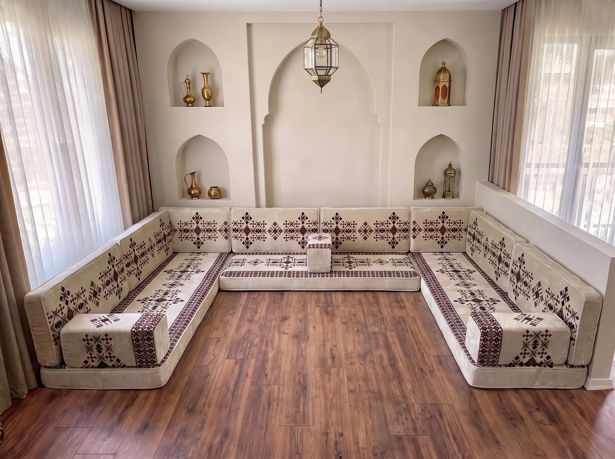 Cream Arabic floor sofa with burgundy sadu motifs in a U shape along three walls, on a bare wooden floor