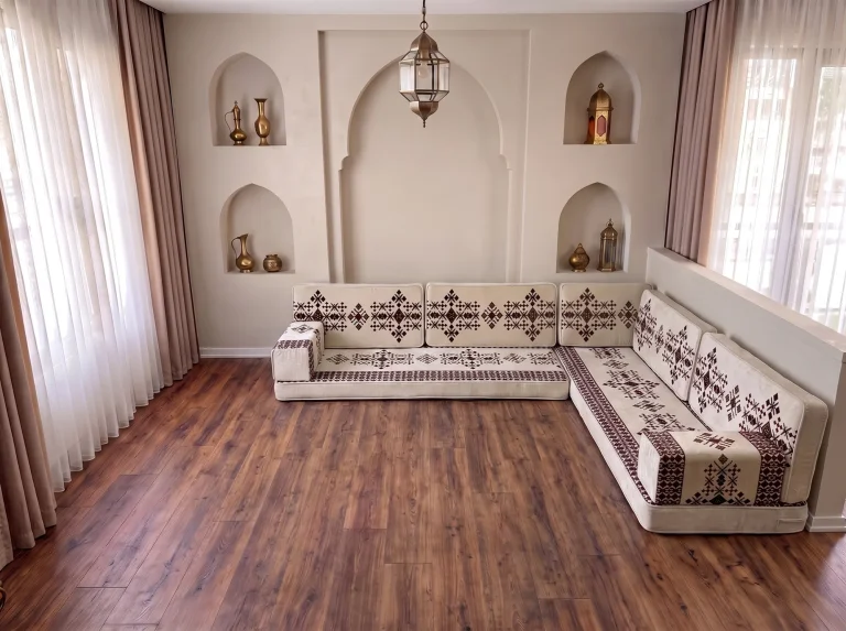 Cream Arabic floor sofa with burgundy sadu motifs in an L shape on a dark wooden floor below arched niches