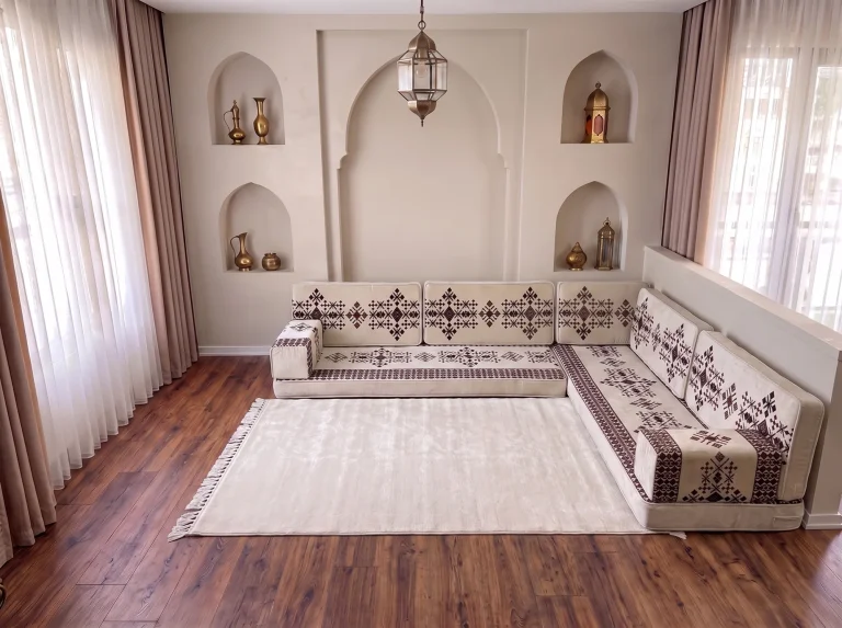 Cream sadu-pattern Arabic floor couch in an L shape with a large plain cream fringed rug in an arched room