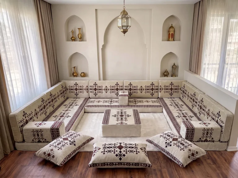 Cream Arabic floor sofa with burgundy sadu embroidery in a U shape, with ottoman, cream rug and floor cushions