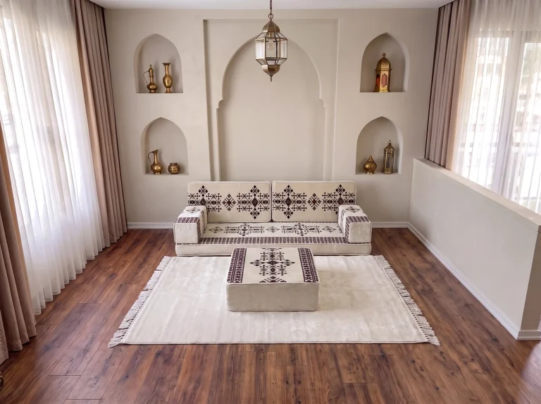 Cream sadu Arabic sofa with a matching sadu-topped ottoman on a cream fringed rug below a brass lantern