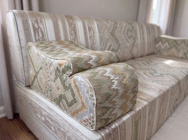Flame-kilim jacquard armrest resting on a beige striped majlis sofa seat, with the backrest behind