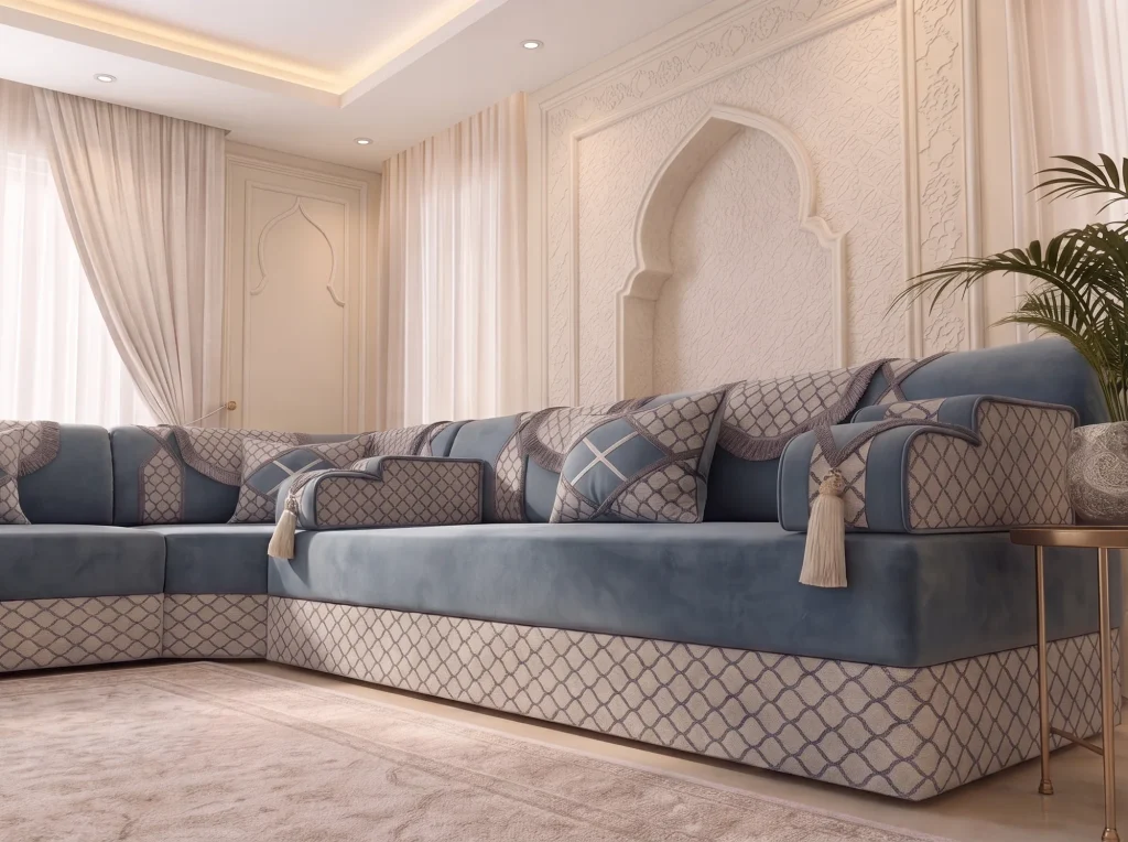 Low side view of a dusty blue majlis sofa with ivory trellis base and tassels below a carved arch wall