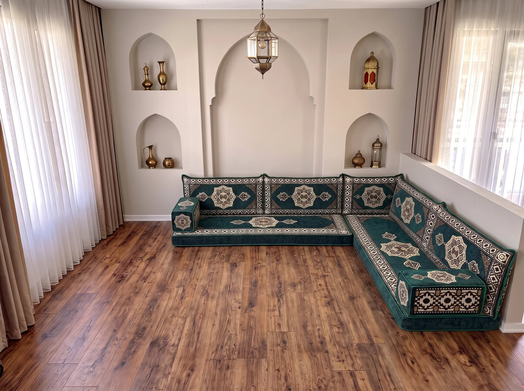 Emerald green and cream medallion floor seating set in an L shape on a bare wood floor in a room with arched wall niches