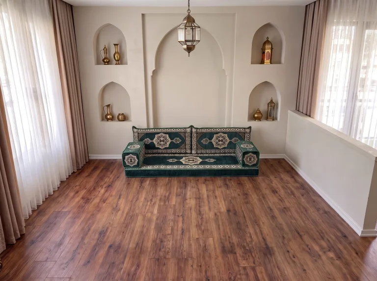 Emerald green and cream medallion Arabic floor sofa as a single row on a bare wood floor in a room with arched wall niches