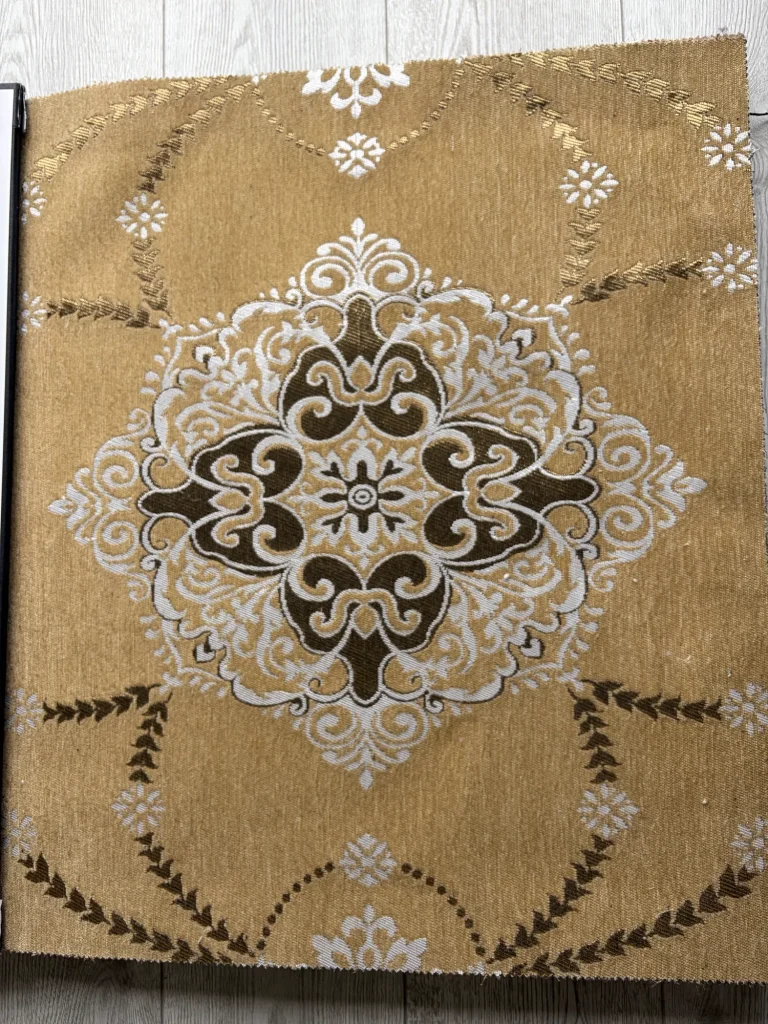 Close view of gold chenille upholstery fabric with a white and dark brown medallion and metallic gold garlands