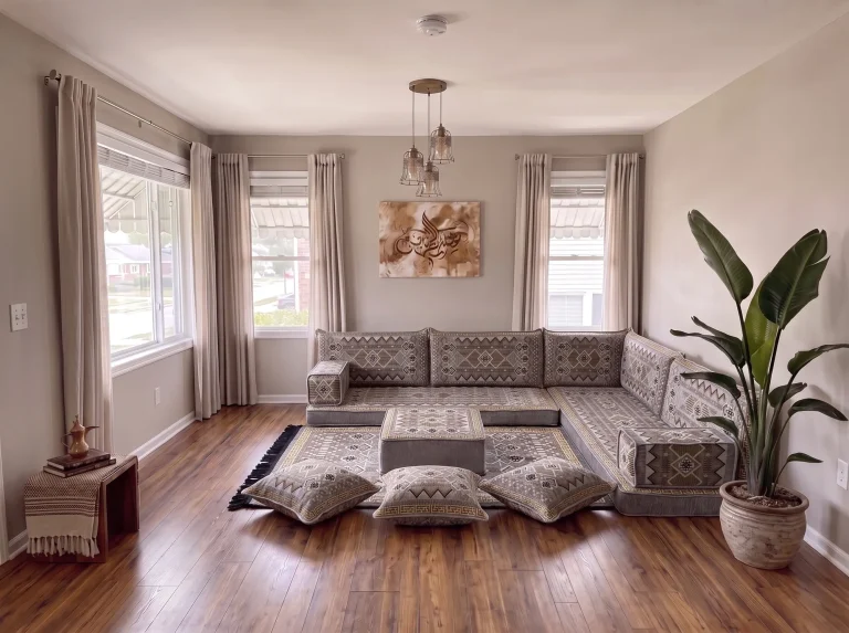 Gray and gold geometric Arabic floor sofa in an L shape with rug, ottoman and floor cushions in a bright living room