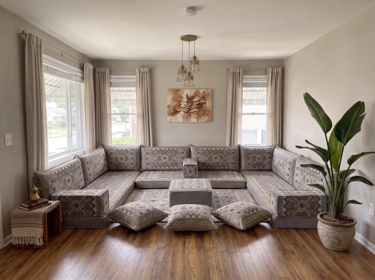 Gray and gold geometric Arabic sofa in a U shape with rug, ottoman and floor cushions in a bright living room