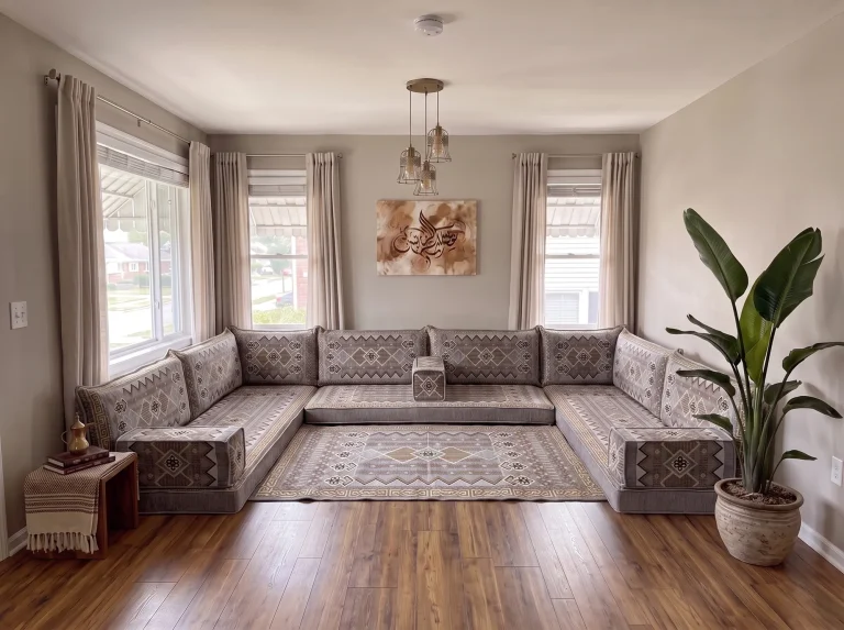 Gray and gold geometric Arabic floor sofa in a U shape with a matching kilim rug in a bright living room with calligraphy art