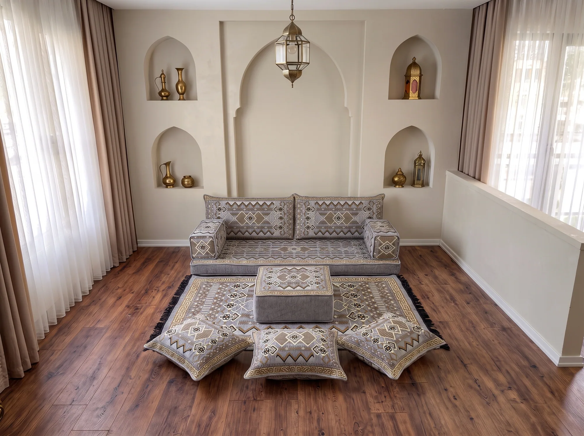Low gray and gold kilim-pattern floor sofa set as a single row with rug, ottoman and floor cushions by arched niches