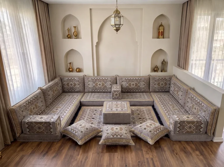 Low gray and gold kilim-pattern Arabic floor sofa in a U shape with rug, ottoman and floor cushions by arched niches