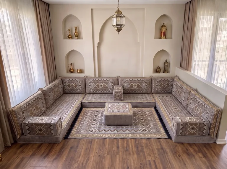Low gray and gold kilim-pattern floor sofa set in a U shape with matching rug and ottoman in a room with arched wall niches
