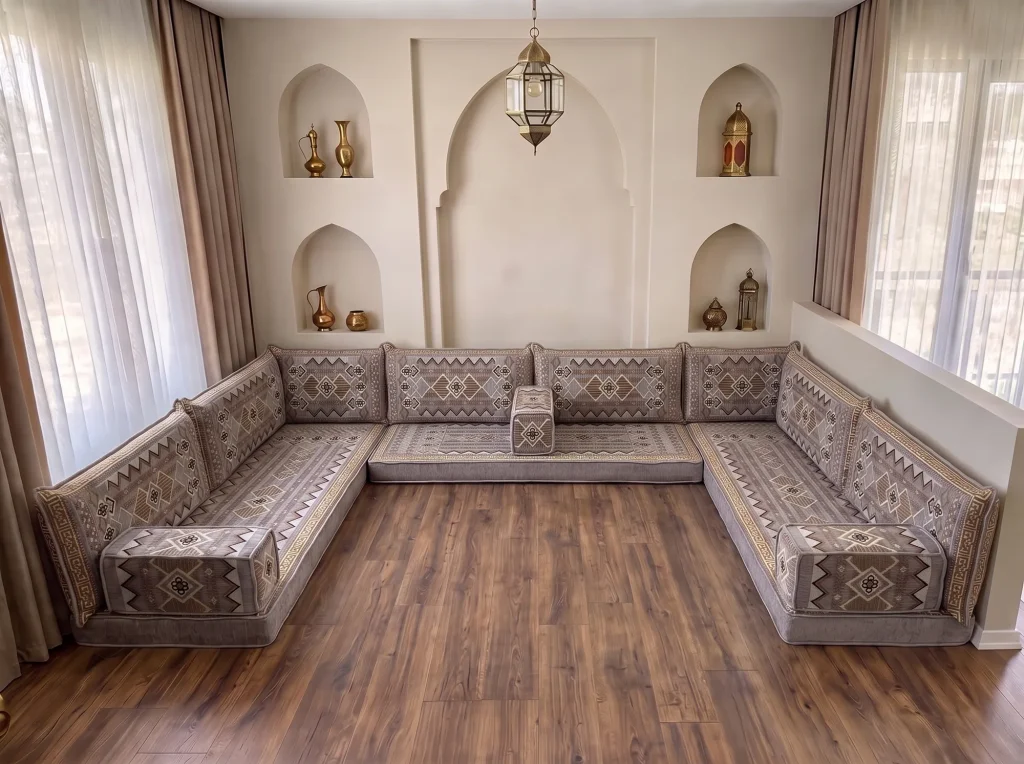 A low grey and gold floor sofa in a U shape in a room with arched niches, the floor-level form suited to a cultural or heritage room