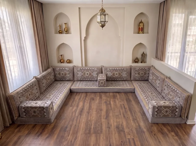 Low gray and gold kilim-pattern floor sofa set in a U shape on a bare wood floor in a room with arched wall niches