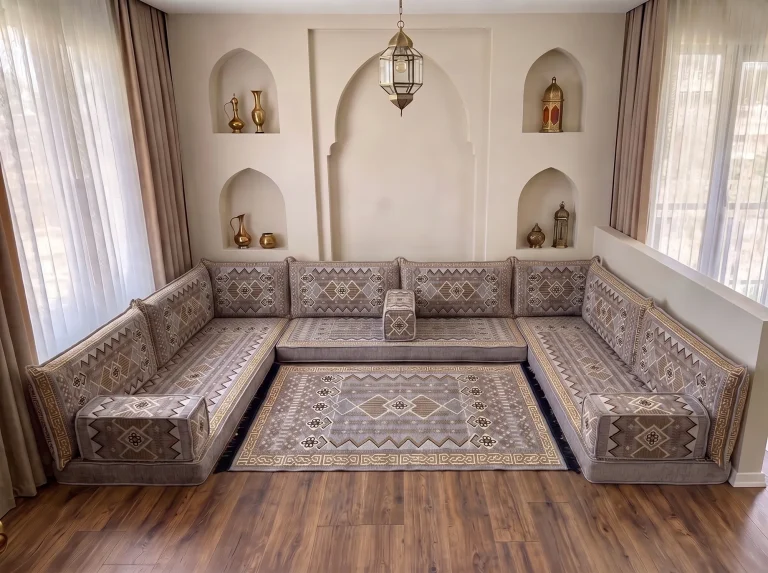 Low gray and gold kilim-pattern Arabic floor couch in a U shape with a matching kilim rug in a room with arched wall niches