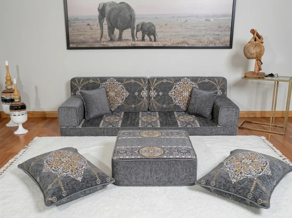 Grey chenille Arabic sofa at floor height with gold medallion cushions, ottoman and floor cushions