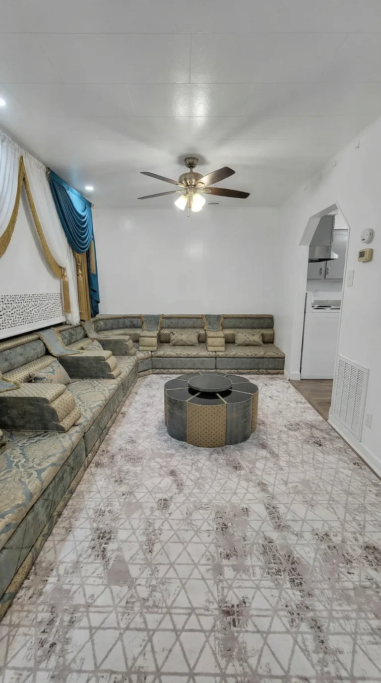 Grey and gold damask majlis sofa along two walls with a round segmented centre table