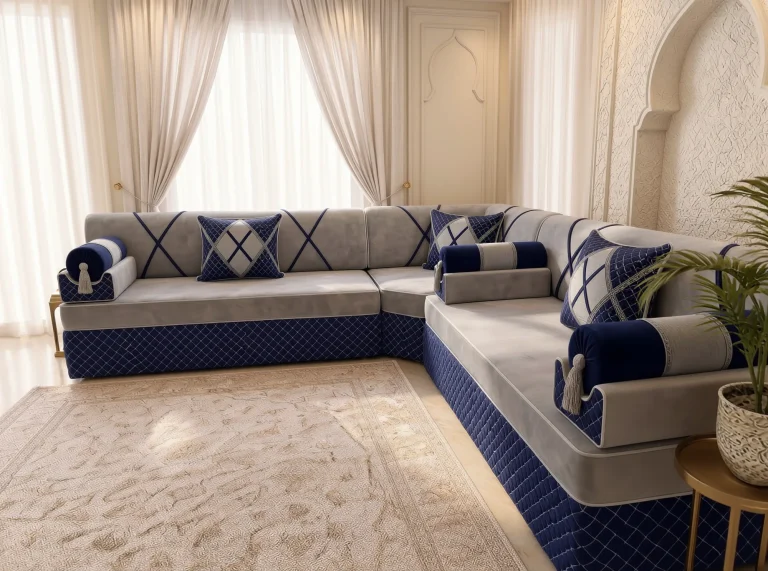 Light grey velvet majlis sofa in an L shape with navy bolster armrests seen along the right arm