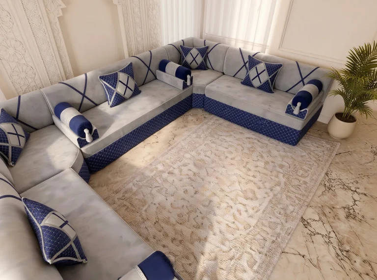 Overhead view of a light grey and navy Arabic majlis corner with bolster armrests on a veined marble floor