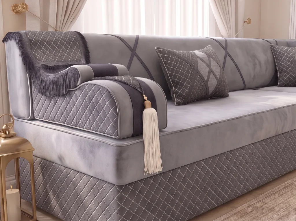 Close-up of a quilted grey armrest with charcoal fringe and a cream tassel on a majlis sofa set